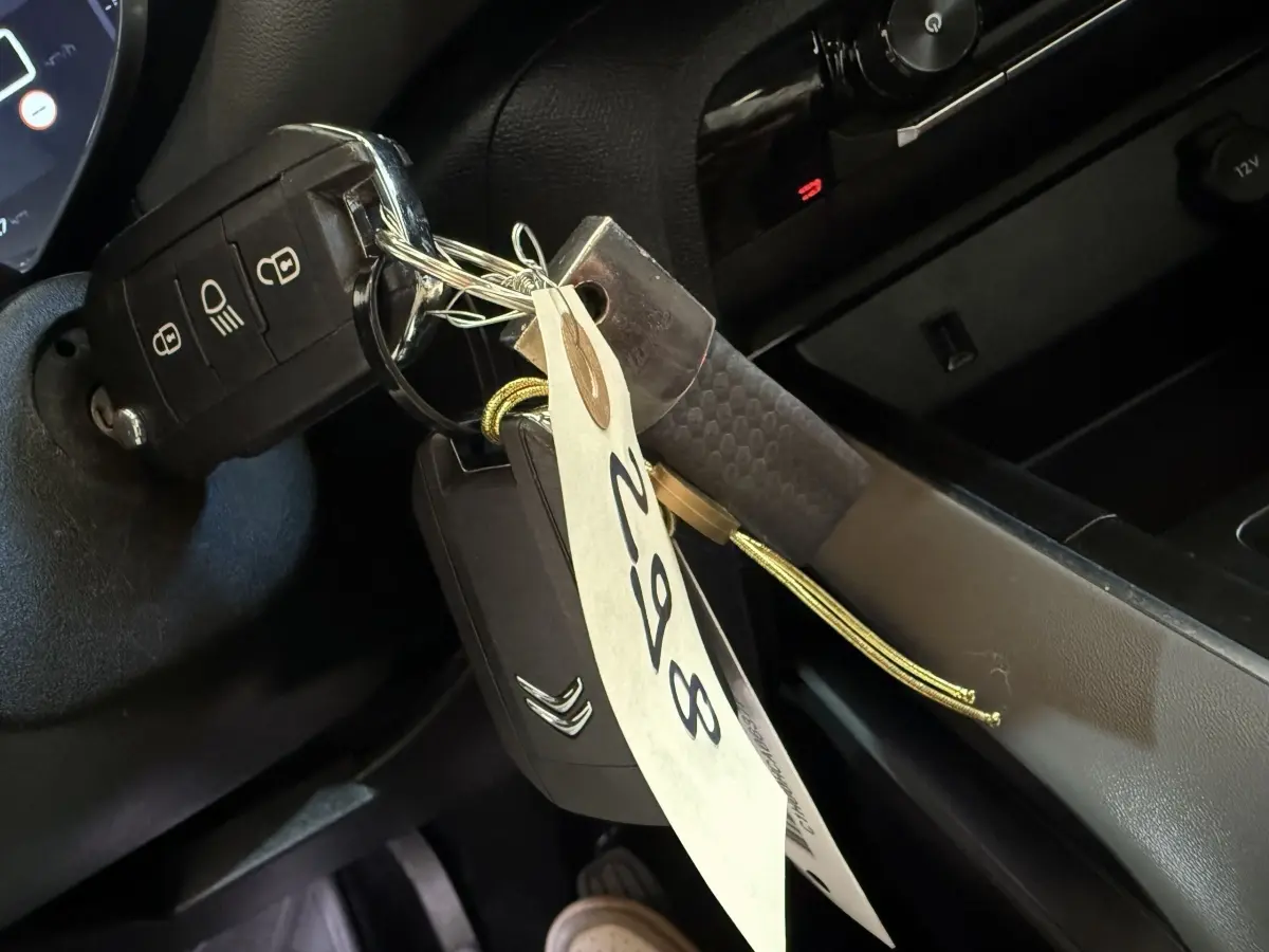 Gros plan sur la clé de contact Citroën insérée dans le contacteur, avec étiquette suspendue dans l’habitacle noir.