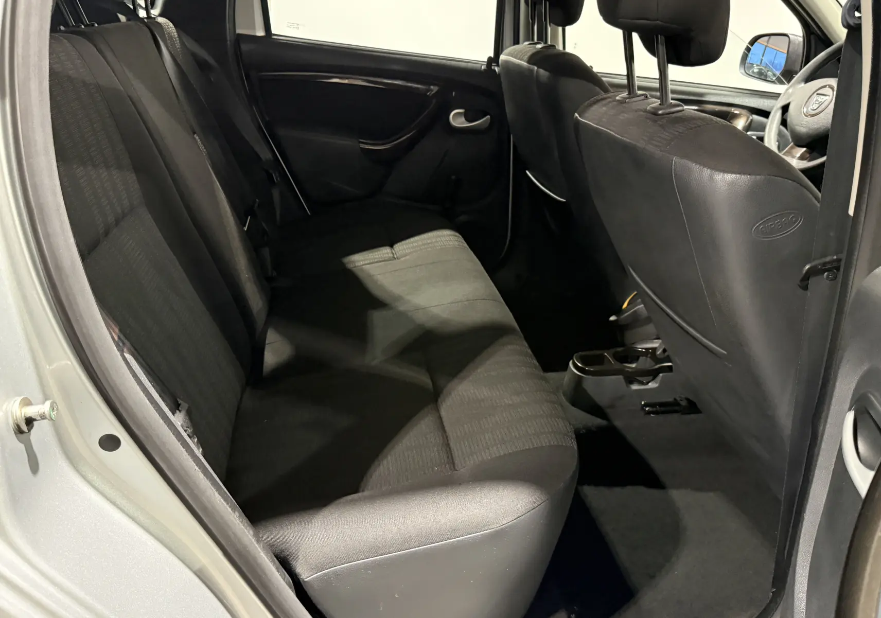 Vue intérieure côté droit sur la banquette arrière et les sièges avant noirs du Dacia Duster gris 2011.