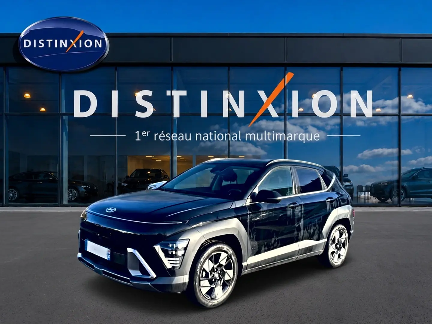 Hyundai Kona 2025 noir en 3/4 avant droit, avec jantes alliage et barres de toit visibles devant showroom Distinxion.