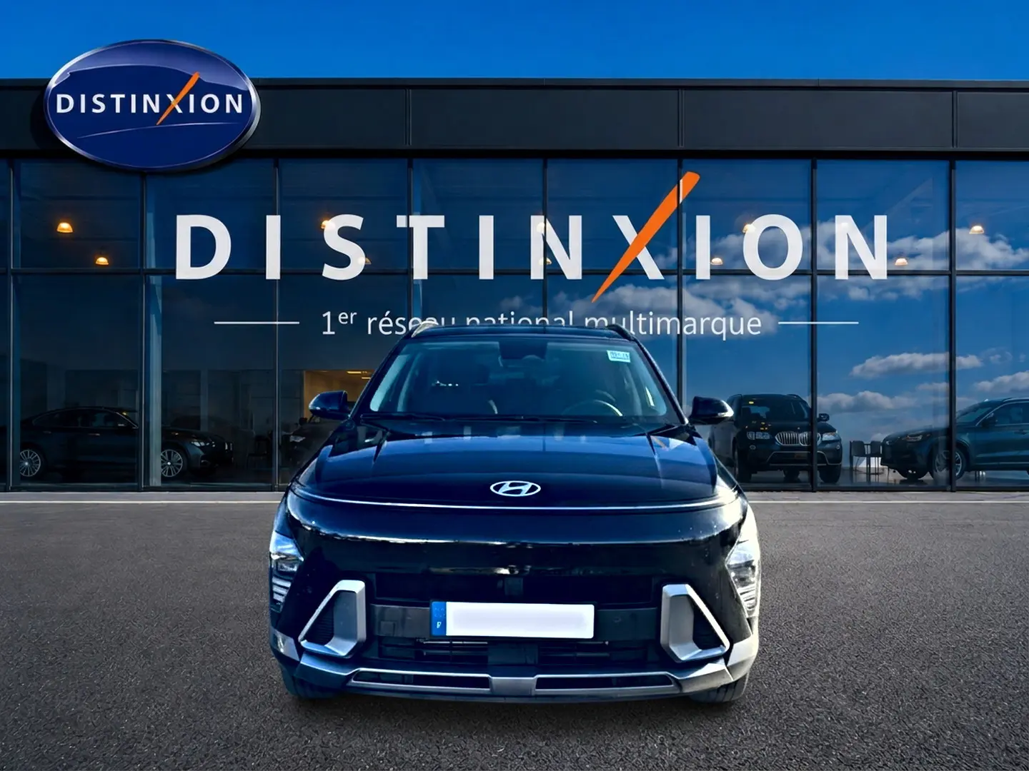 Vue frontale d'un Hyundai Kona noir 2025 avec calandre et phares LED distinctifs, devant une vitrine Distinxion.