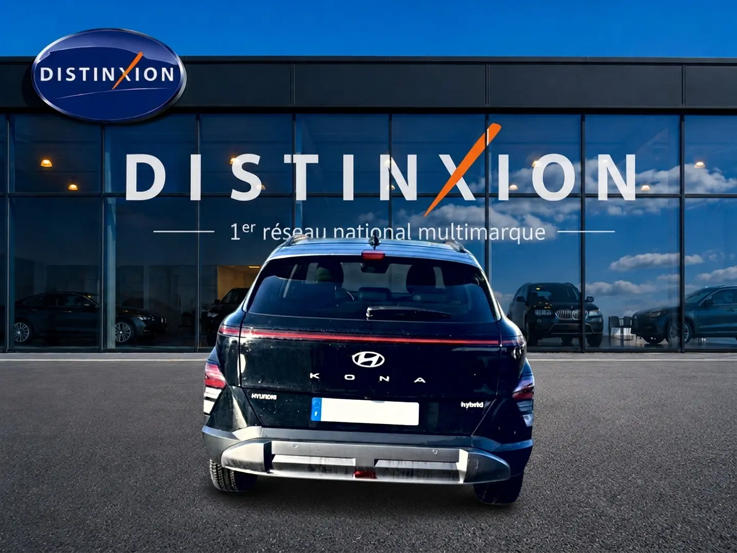 Vue arrière d'un Hyundai Kona noir hybride 2025 avec bande lumineuse LED et logo visible devant une vitrine Distinxion.