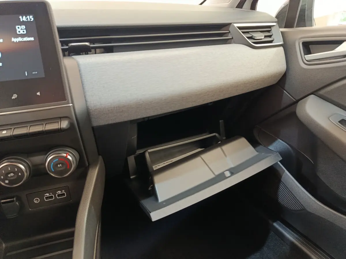 Intérieur de la Renault Clio 2024, vue du côté passager avec boîte à gants ouverte et tableau de bord gris clair.