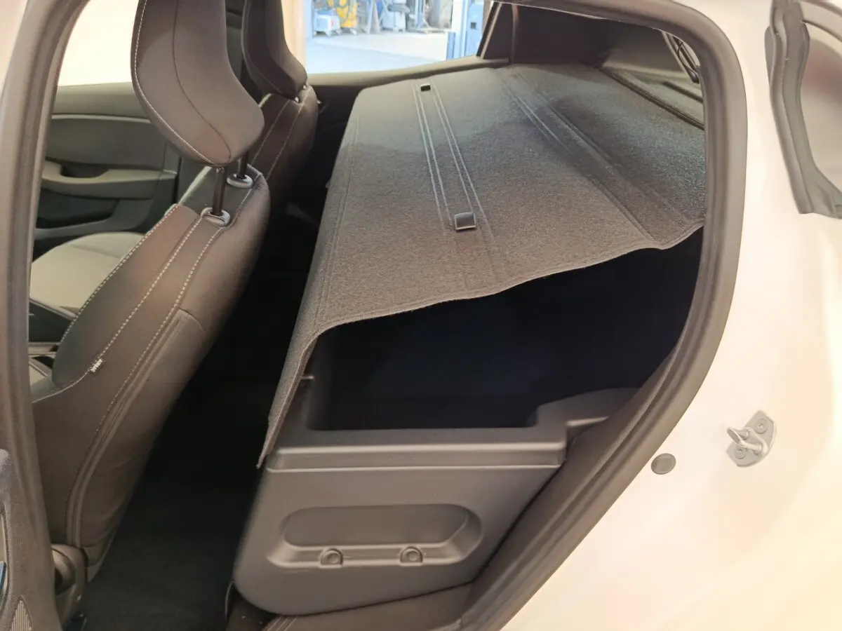Vue intérieure côté droit de la Renault Clio blanche 2024 montrant le coffre sous la banquette arrière rabattue.
