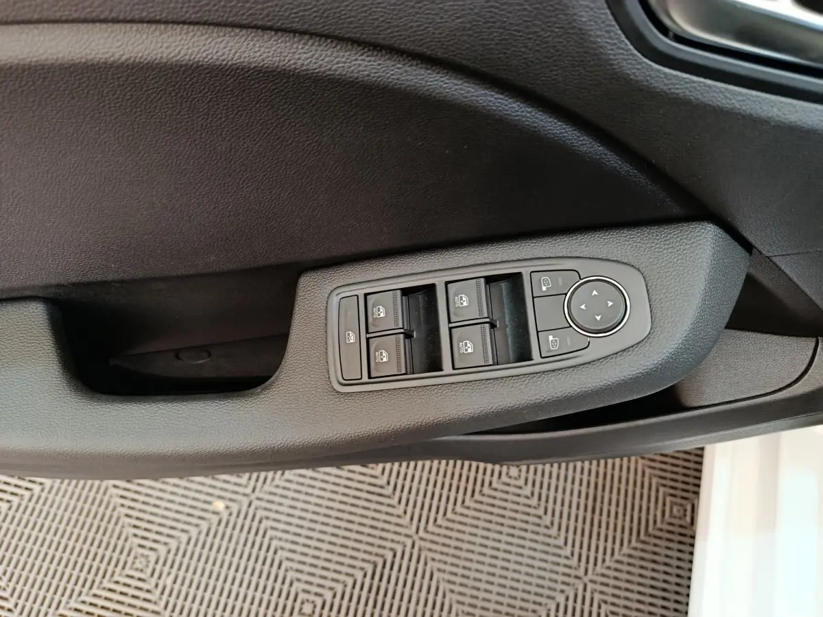 Vue rapprochée des commandes de lève-vitres et réglages des rétroviseurs sur la porte côté conducteur d'une Renault Clio blanche.