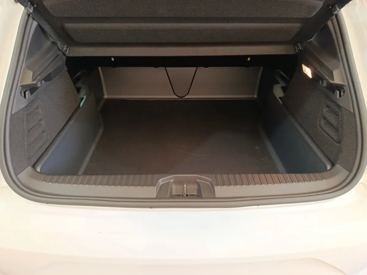 Coffre ouvert vu de l'arrière d'une Renault Clio blanche 2024, espace de chargement vide et éclairage intérieur allumé.