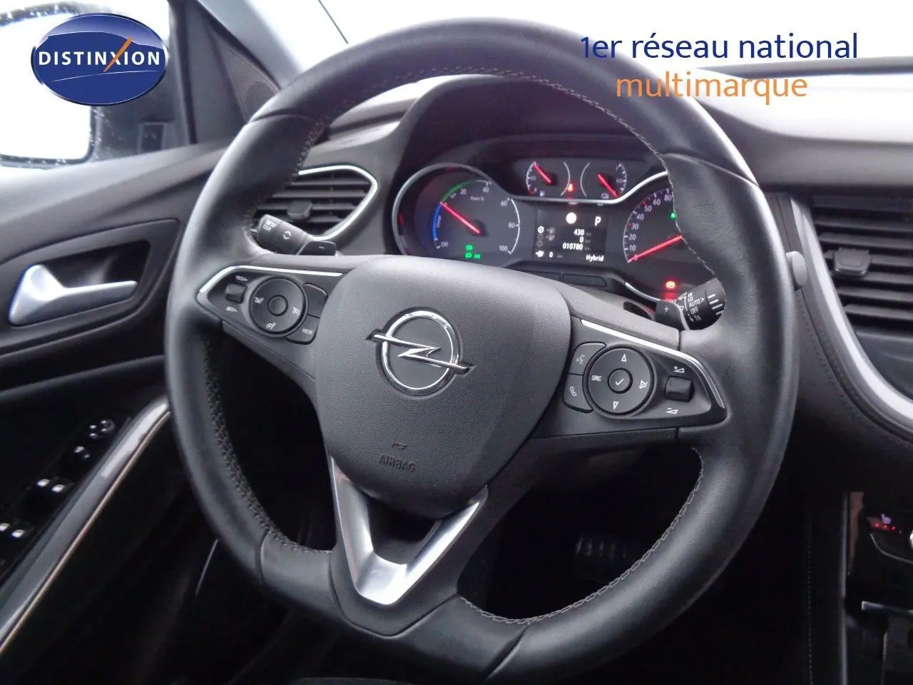 Vue rapprochée du volant noir de l’Opel Grandland X hybride, avec tableau de bord et commandes visibles.