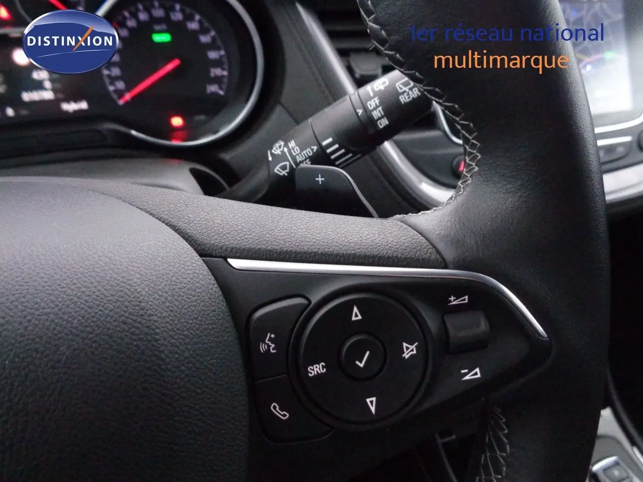 Gros plan sur le volant en cuir noir de l’Opel Grandland X 1.6 Hybrid Turbo, avec commandes multifonctions visibles.