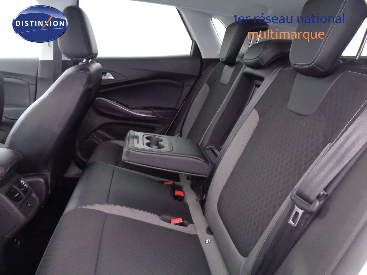 Vue intérieure côté droit des sièges arrière noirs et gris avec accoudoir central déployé de l’Opel Grandland X hybride rechargeable.
