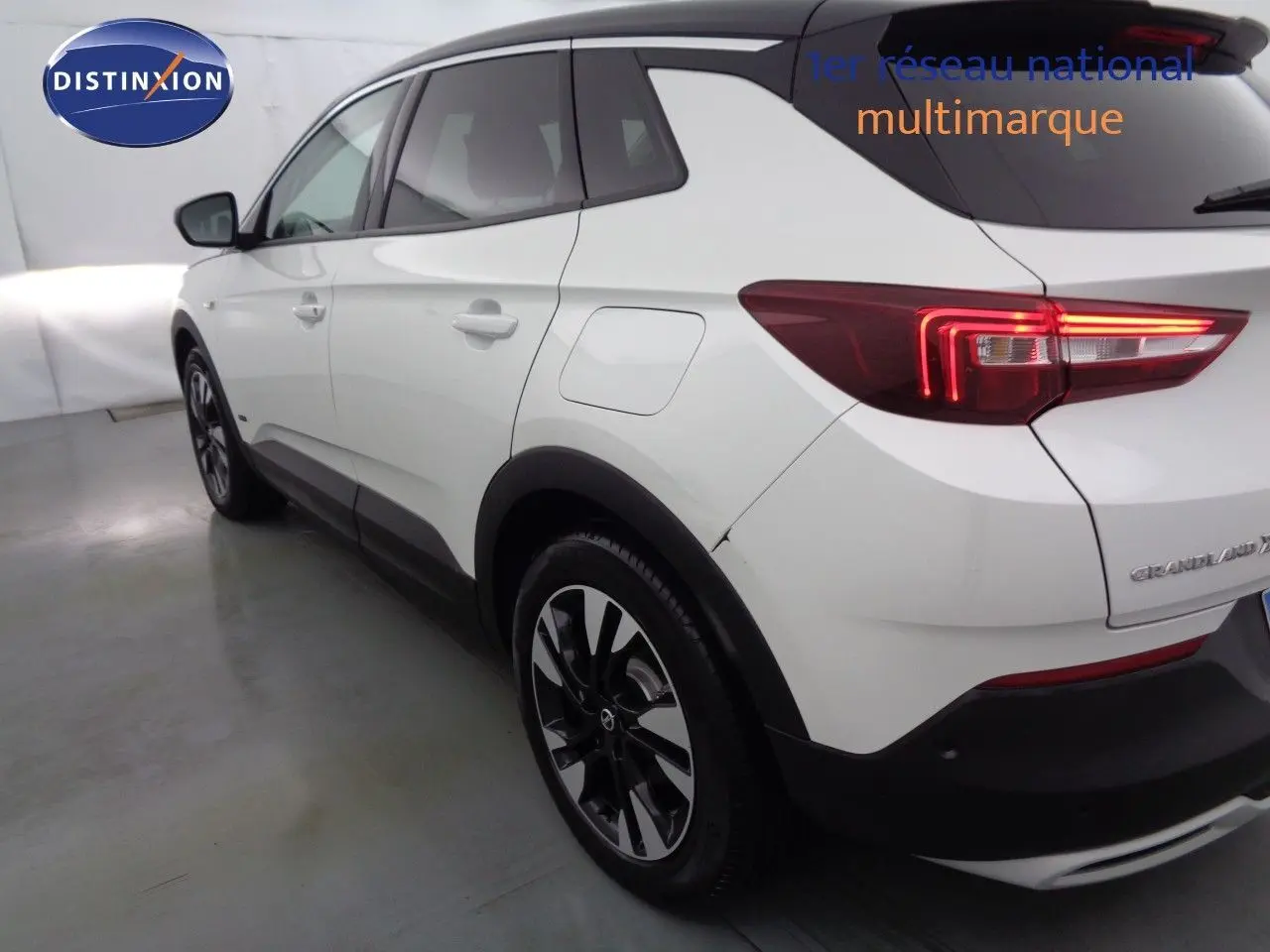 Vue 3/4 arrière droite d’un Opel Grandland X blanc métal avec feux LED allumés en intérieur.