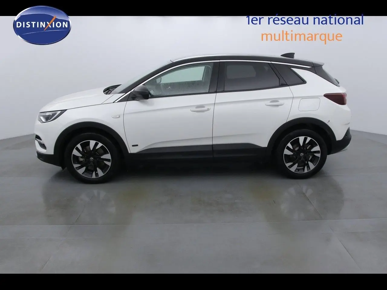 Opel Grandland X blanc métal vu de profil côté gauche, avec jantes bicolores et toit noir contrastant.