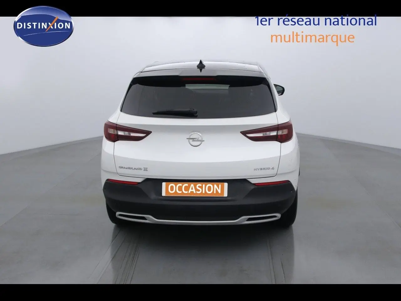 Vue arrière d'un Opel Grandland X blanc métal hybride rechargeable avec feux arrière LED et plaque "OCCASION".