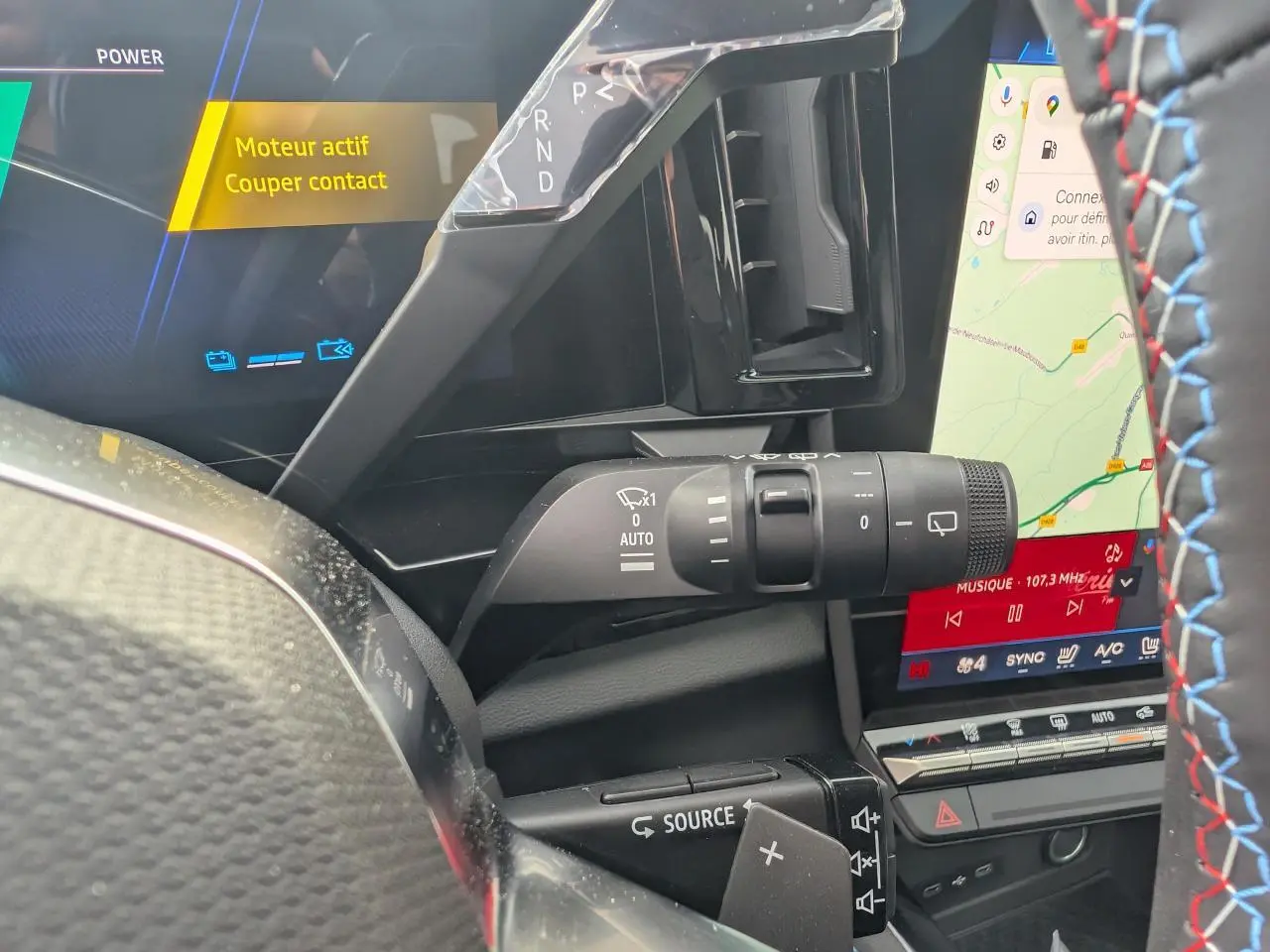 Gros plan sur la commande d'essuie-glace et le volant avec surpiqûres tricolores du Renault Austral rouge métallisé 2025.