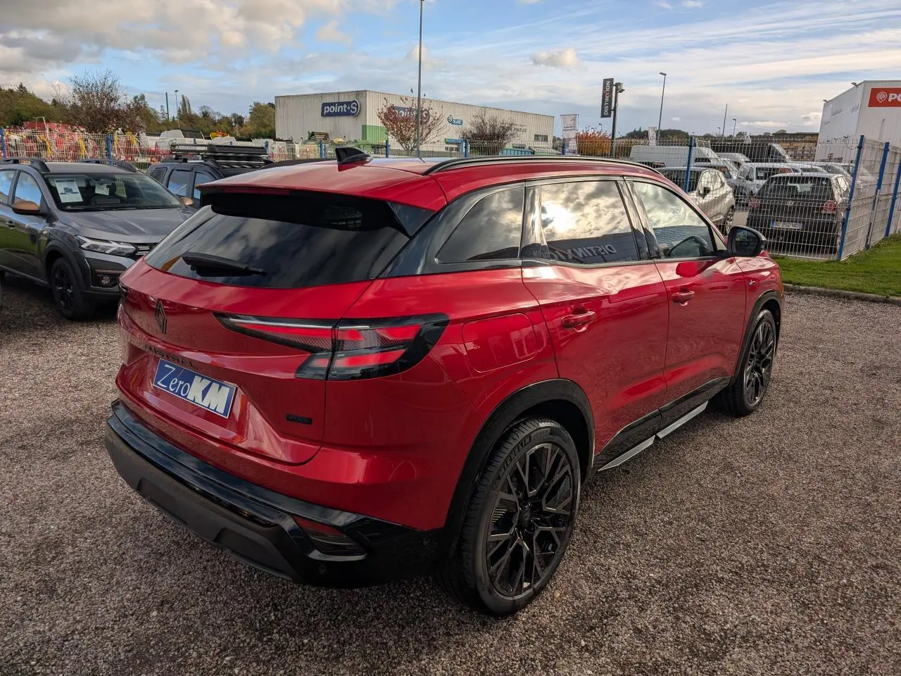 Vue 3/4 arrière droite d'un Renault Austral rouge métallisé avec jantes noires et vitres teintées.