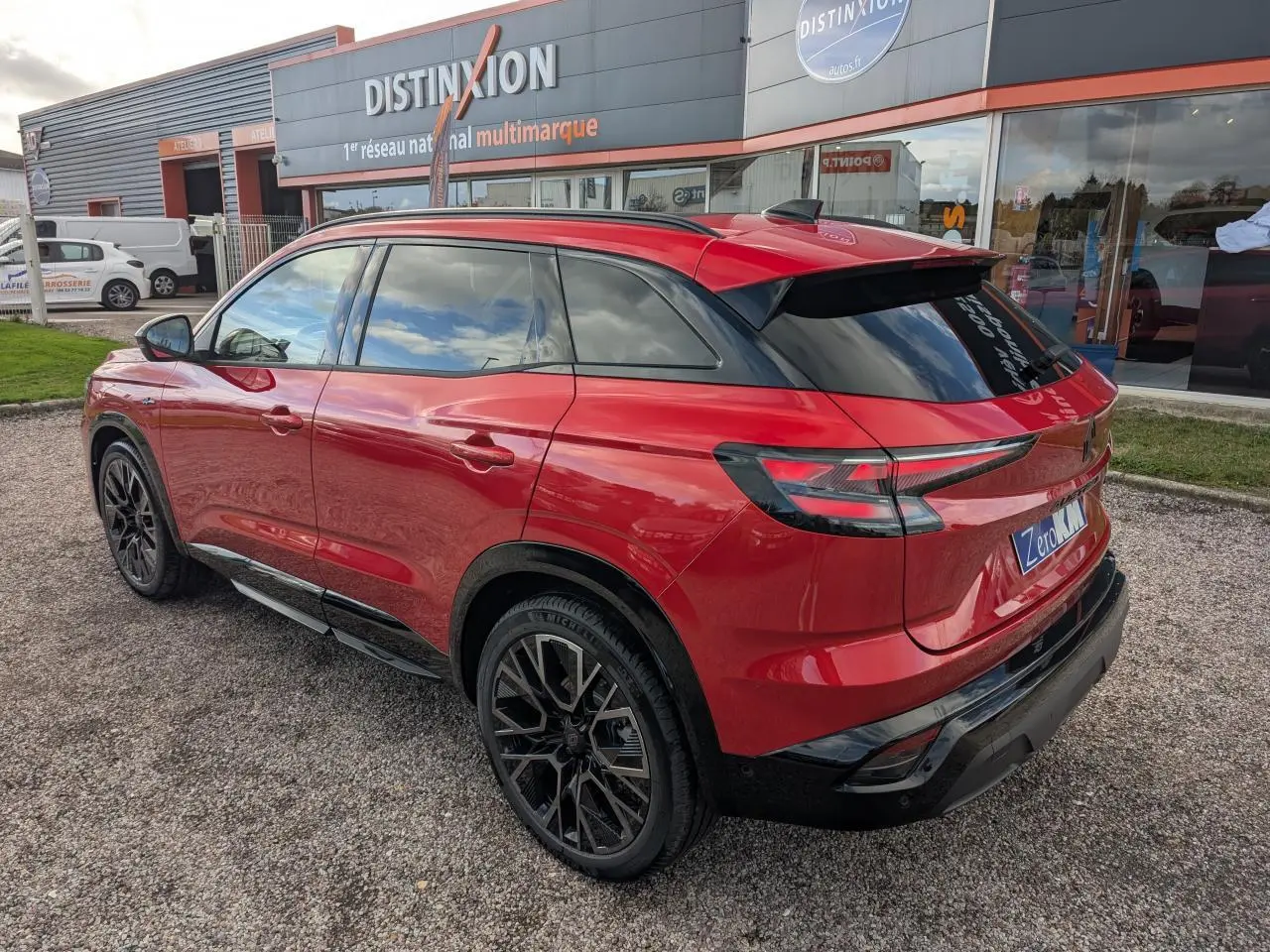 Vue 3/4 arrière droite du Renault Austral rouge métallisé avec jantes noires et toit panoramique fixe.