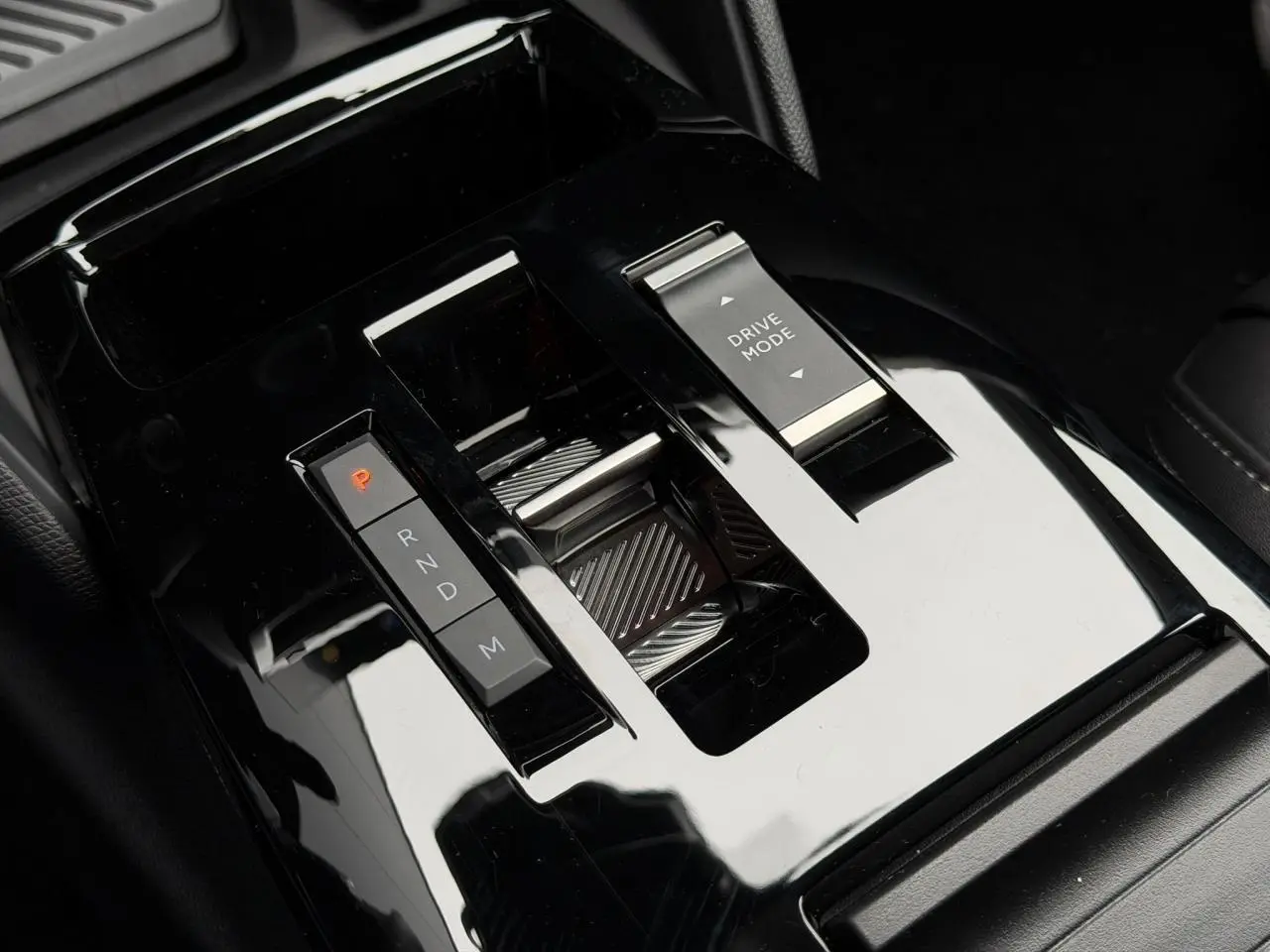 Gros plan sur la console centrale noire brillante du Citroën C4 2025, avec commandes de boîte auto et mode de conduite.