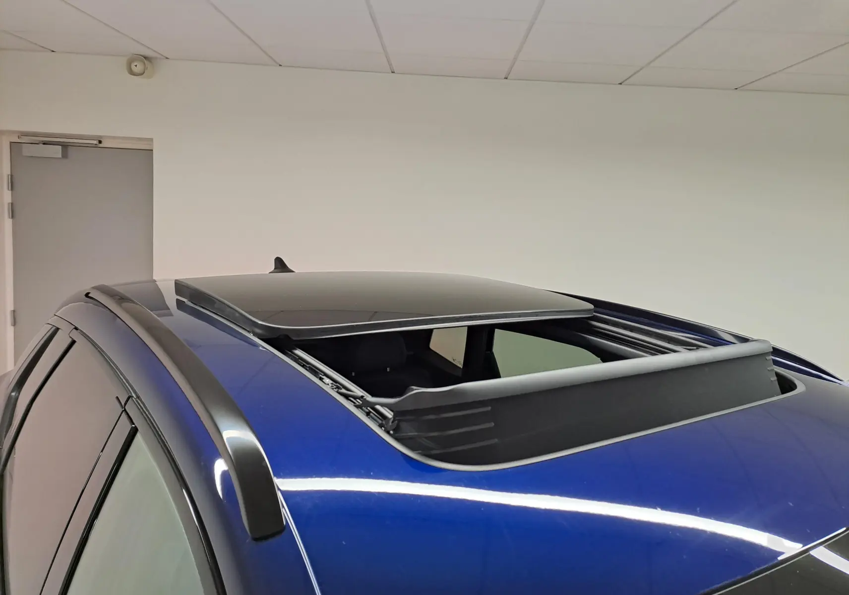 Vue rapprochée du toit ouvrant panoramique du CUPRA TERRAMAR 2025 en Bleu Cosmos, avec rails de toit noirs visibles.