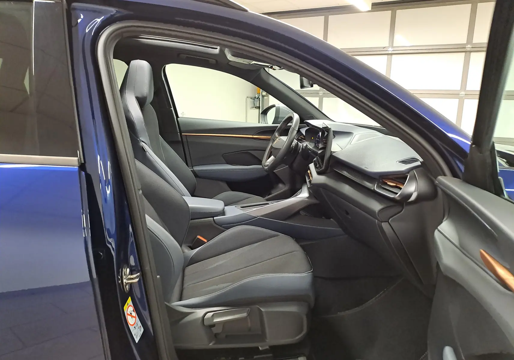 Vue intérieure côté gauche de la CUPRA TERRAMAR bleu Cosmos, montrant les sièges avant et le tableau de bord moderne.