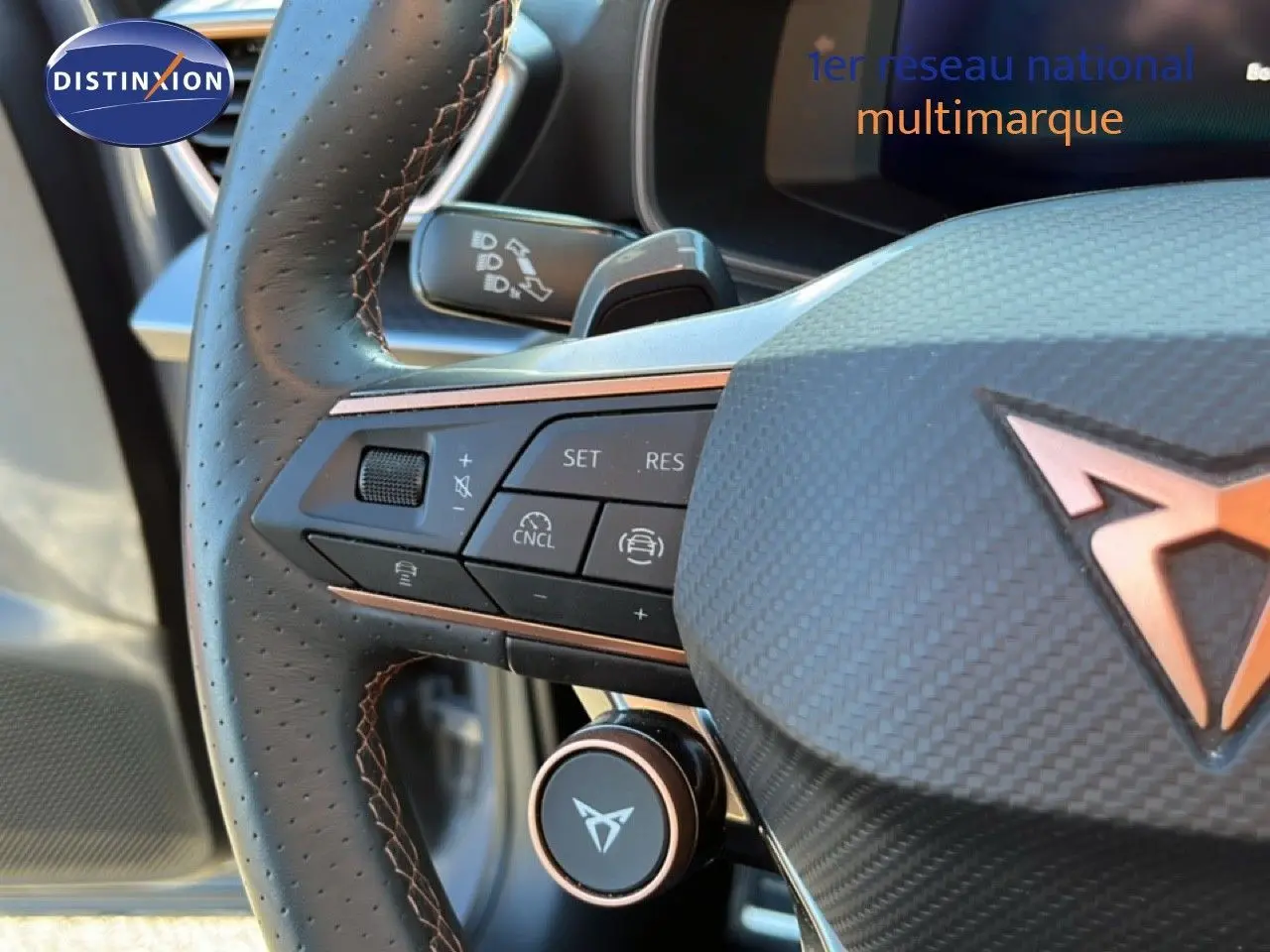 Gros plan sur le volant cuir noir perforé avec surpiqûres cuivrées du CUPRA Formentor gris magnétique, mettant en valeur les commandes intégrées.