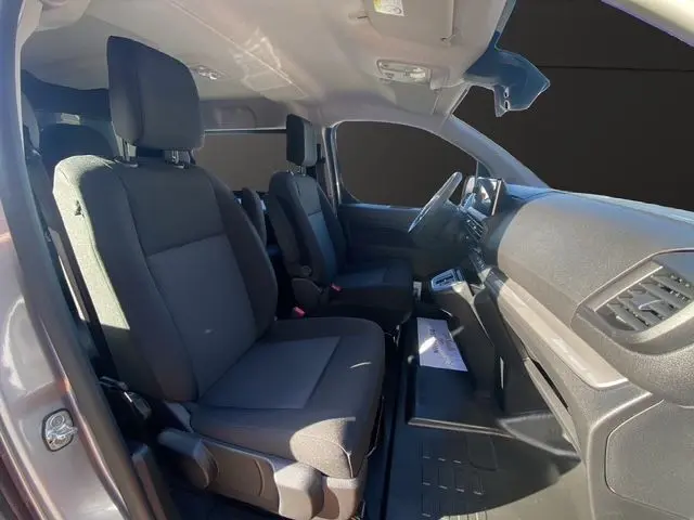 Vue intérieure côté conducteur du Peugeot Expert XL gris acier 2025, sièges tissu noir et tableau de bord moderne.