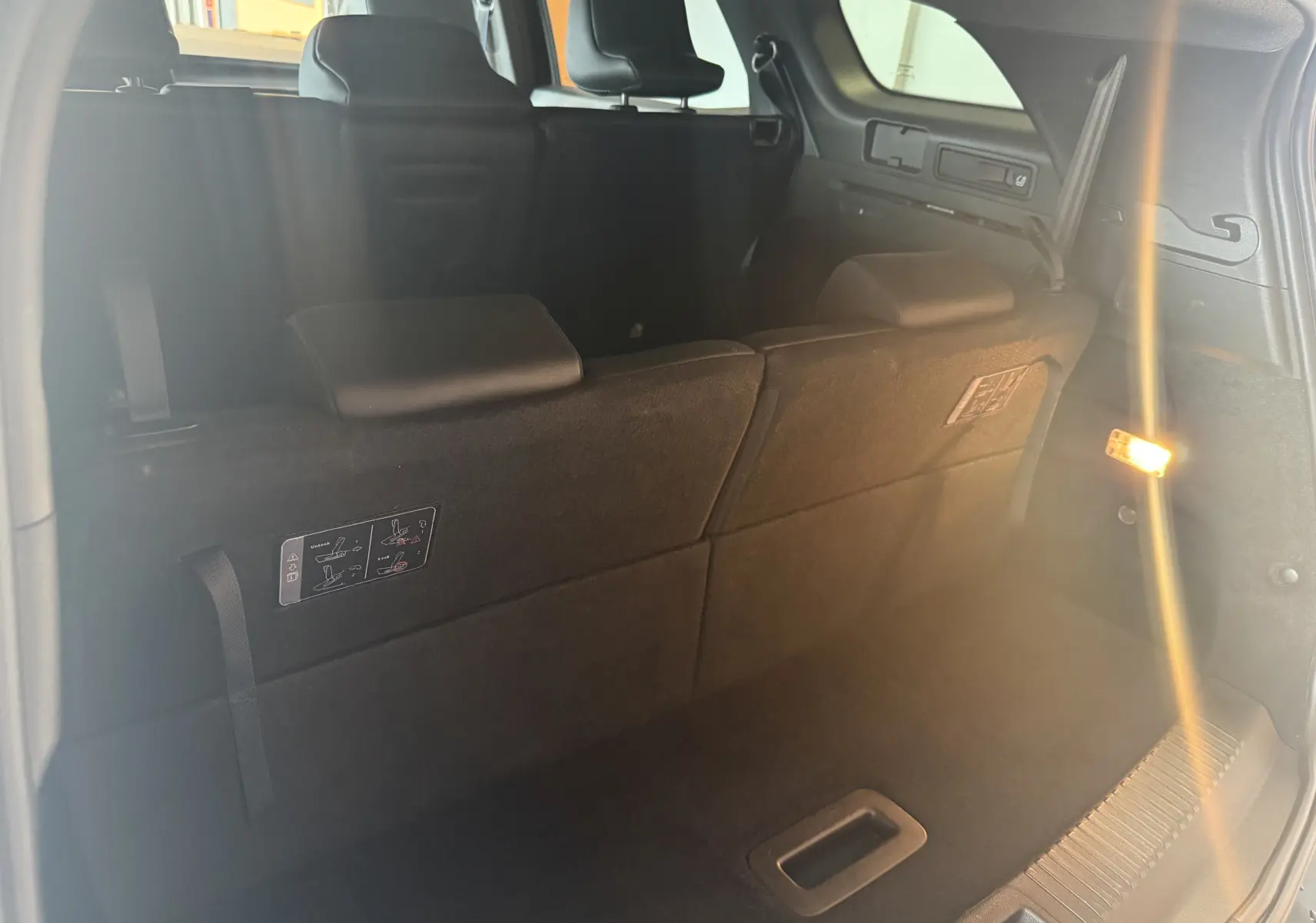 Vue intérieure du coffre arrière du Renault Espace VI E-Tech 200 Esprit Alpine noir, sièges rabattus et éclairage latéral allumé.