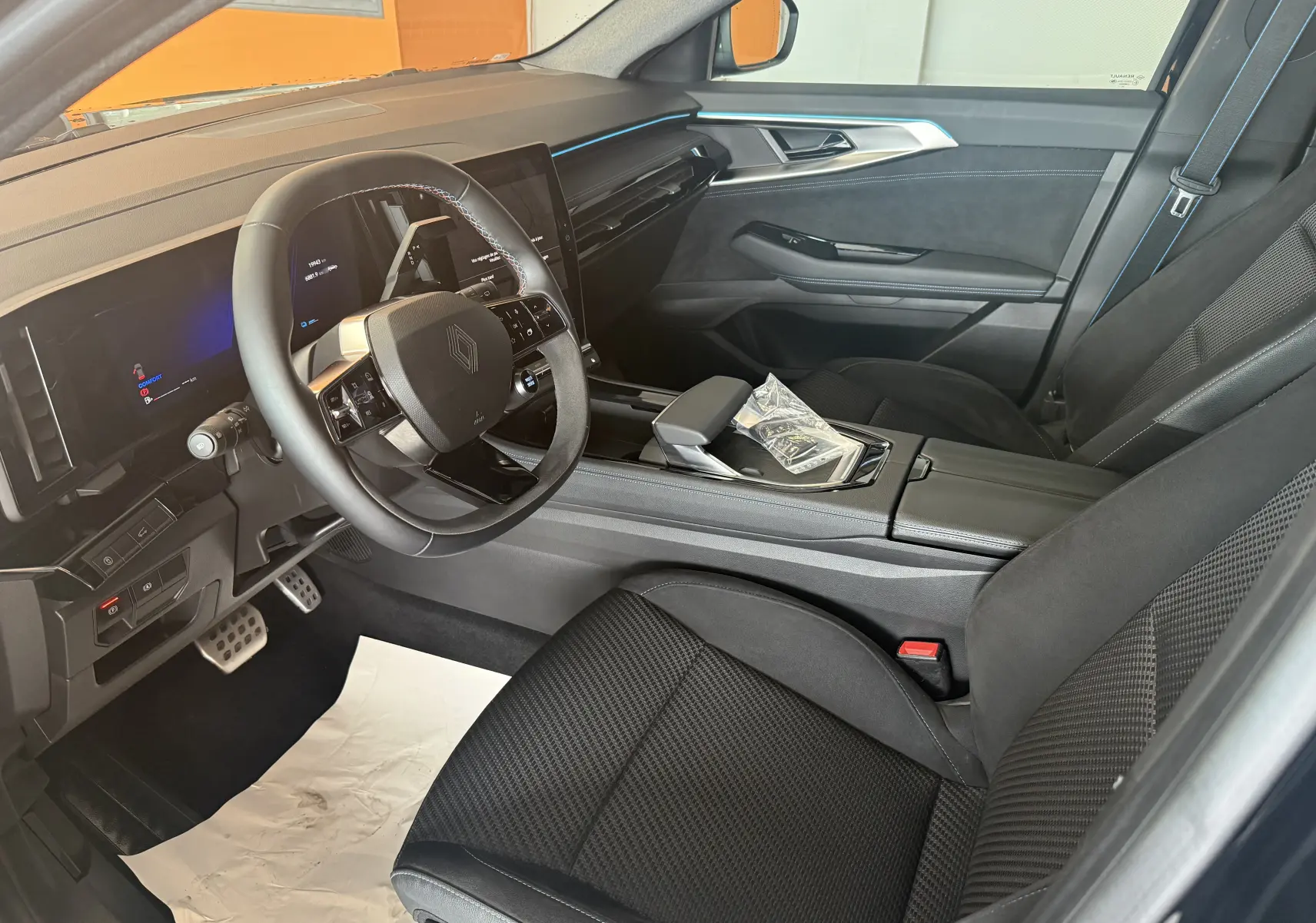 Vue intérieure côté conducteur du Renault Espace VI E-Tech 200 Esprit Alpine noir, avec volant compact et écran tactile central.