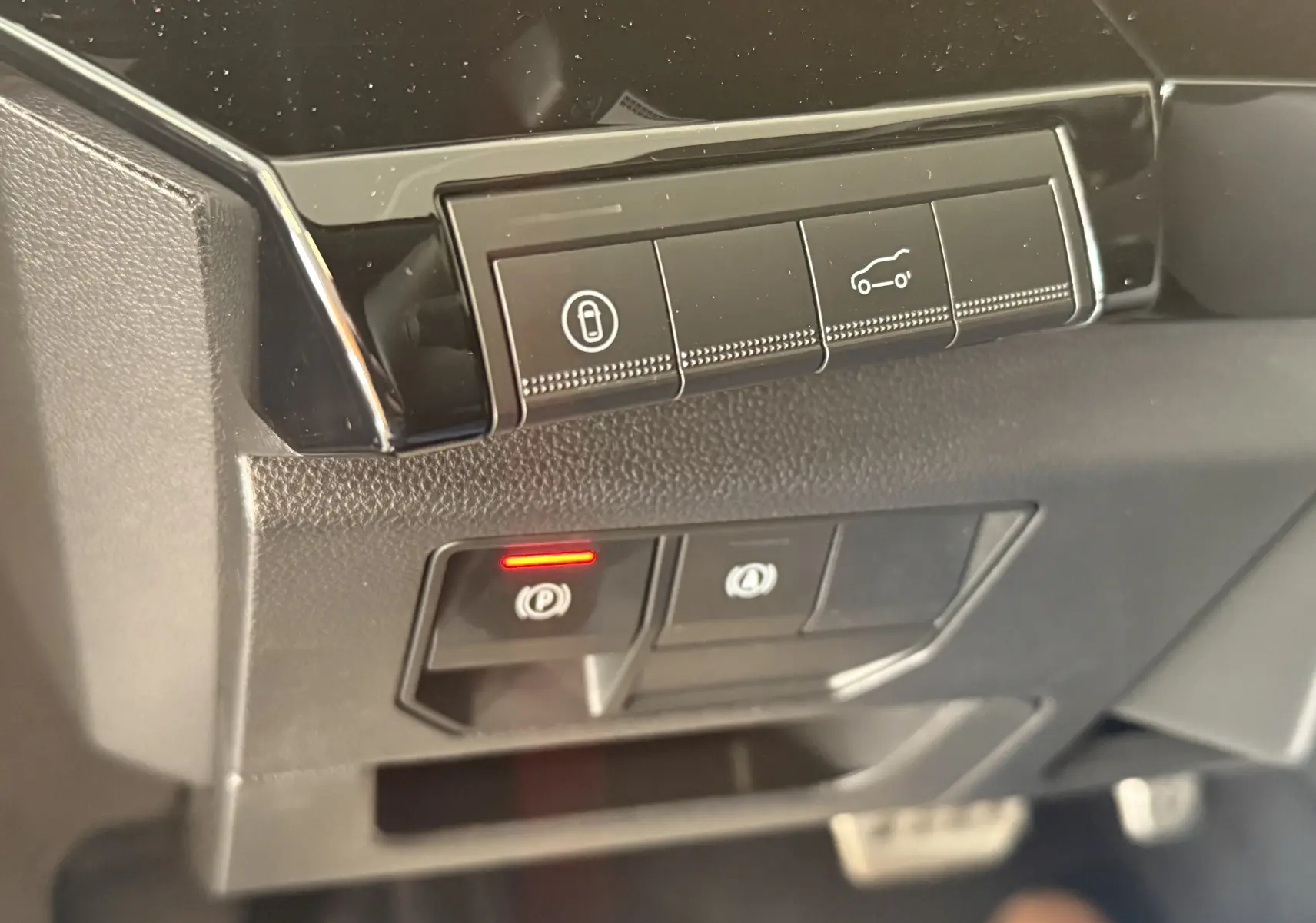 Gros plan sur les commandes de tableau de bord noir du Renault Espace VI E-Tech 200 Esprit Alpine, avec bouton frein à main rouge allumé.