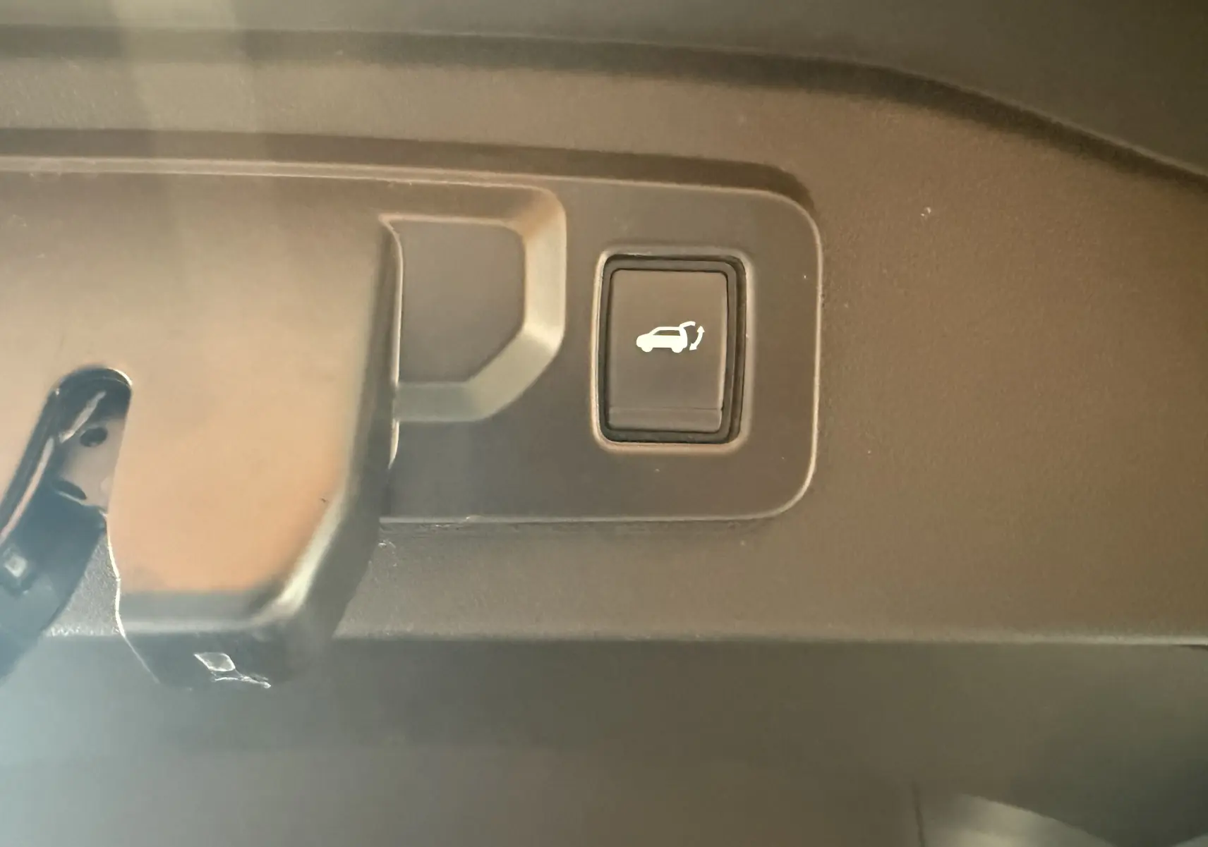 Bouton d'ouverture électrique du hayon visible en gros plan à l'intérieur du coffre du Renault Espace VI noir.