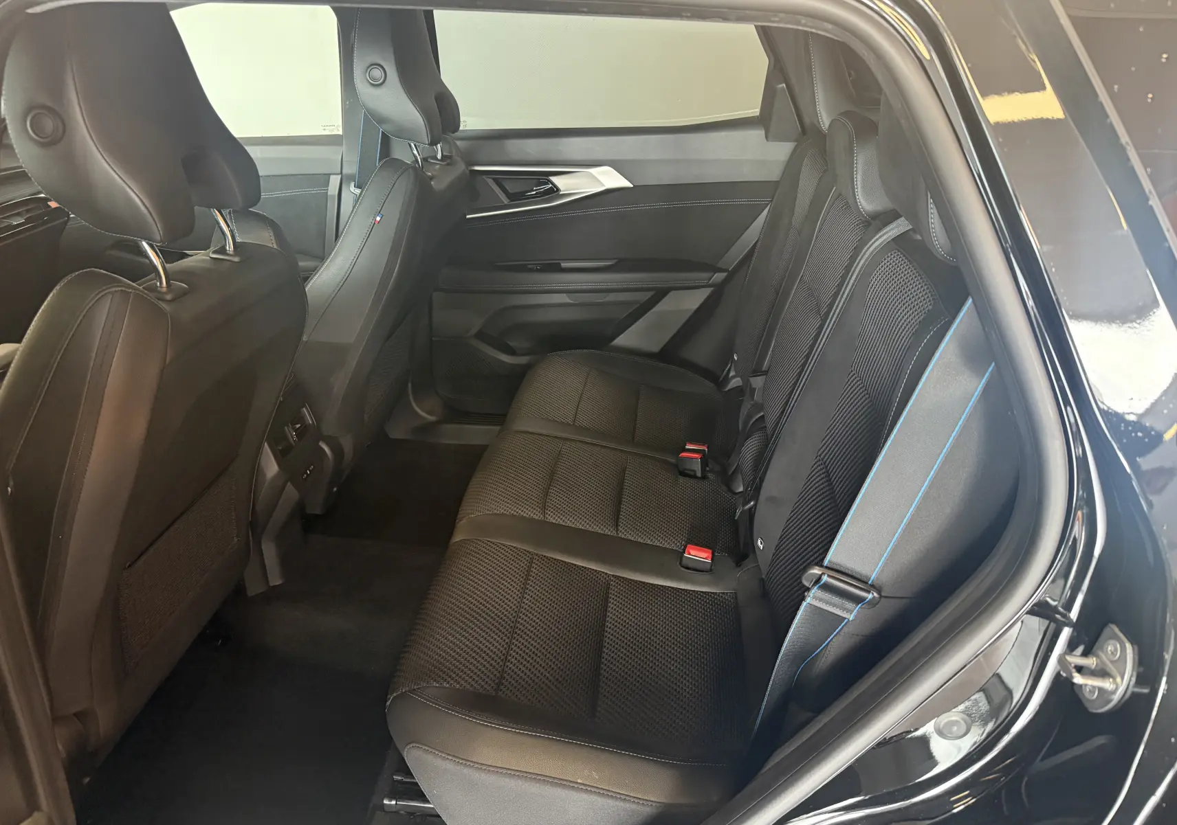Vue côté droit de l'intérieur arrière noir du Renault Espace VI E-Tech 200 Esprit Alpine avec surpiqûres bleues.