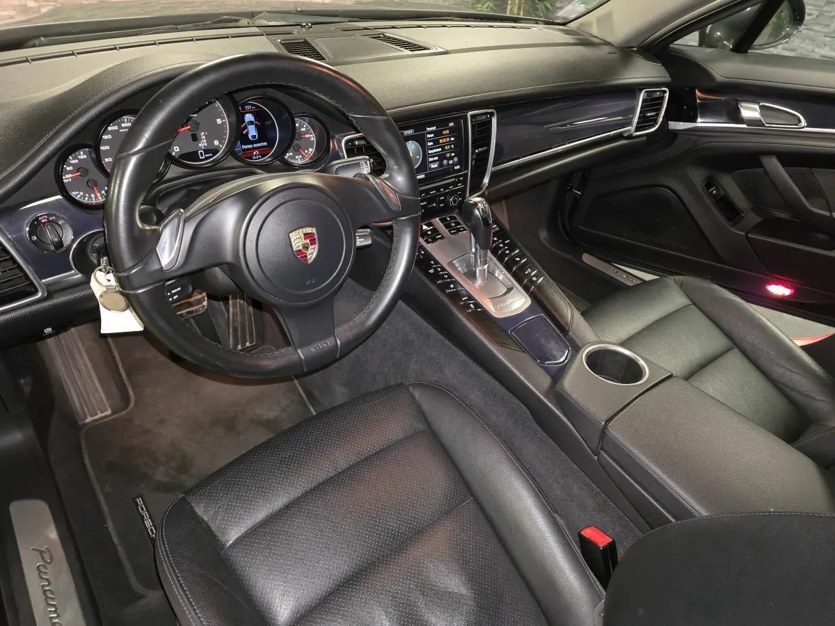 Vue intérieure côté conducteur de la Porsche Panamera 2011, cuir noir, console centrale avec levier de vitesse Tiptronic.