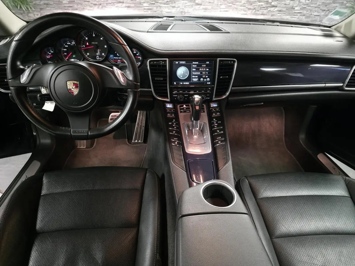 Intérieur avant noir d’une Porsche Panamera 2011, vue centrale sur le tableau de bord et la console avec levier de vitesse.