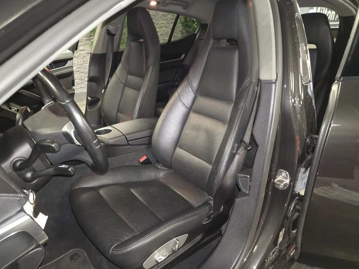 Vue intérieure côté conducteur de la Porsche Panamera marron, sièges cuir noir et volant sport à 3 branches.