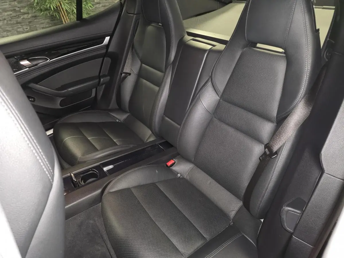 Vue intérieure des sièges avant en cuir noir de la Porsche Panamera 3.0 V6 TDI, avec console centrale et porte-gobelet.