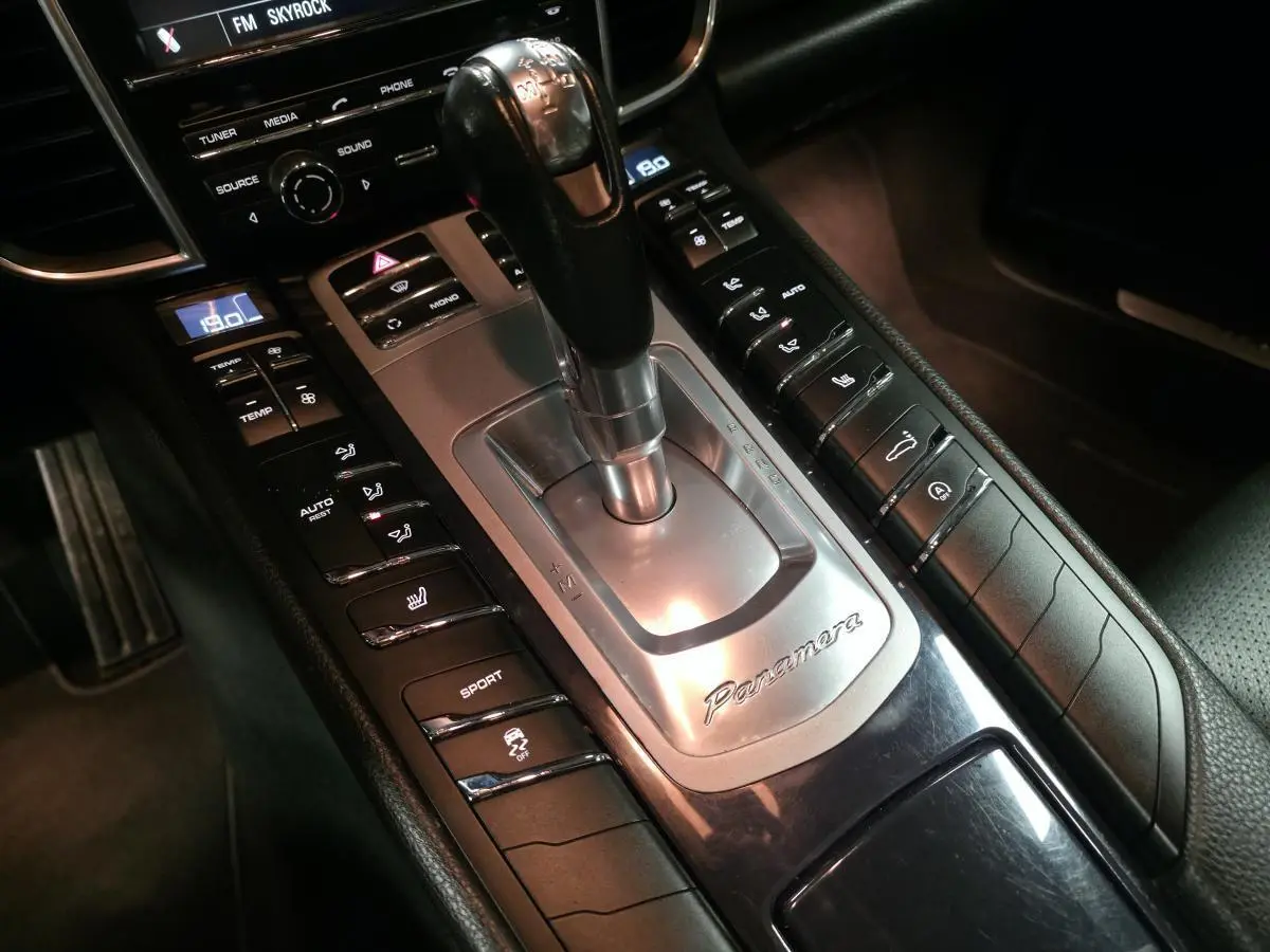 Gros plan sur la console centrale intérieure noire de la Porsche Panamera marron, avec levier de vitesse et commandes sport visibles.