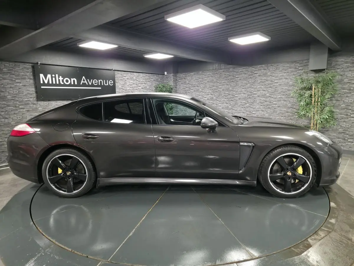 Vue latérale droite d'une Porsche Panamera marron métallisée avec jantes noires sport et étriers de frein jaunes.
