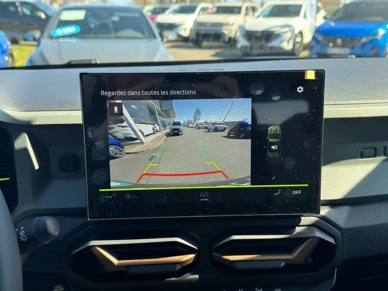 Vue intérieure du tableau de bord du Dacia Duster blanc 2025, écran tactile affichant la caméra de recul.
