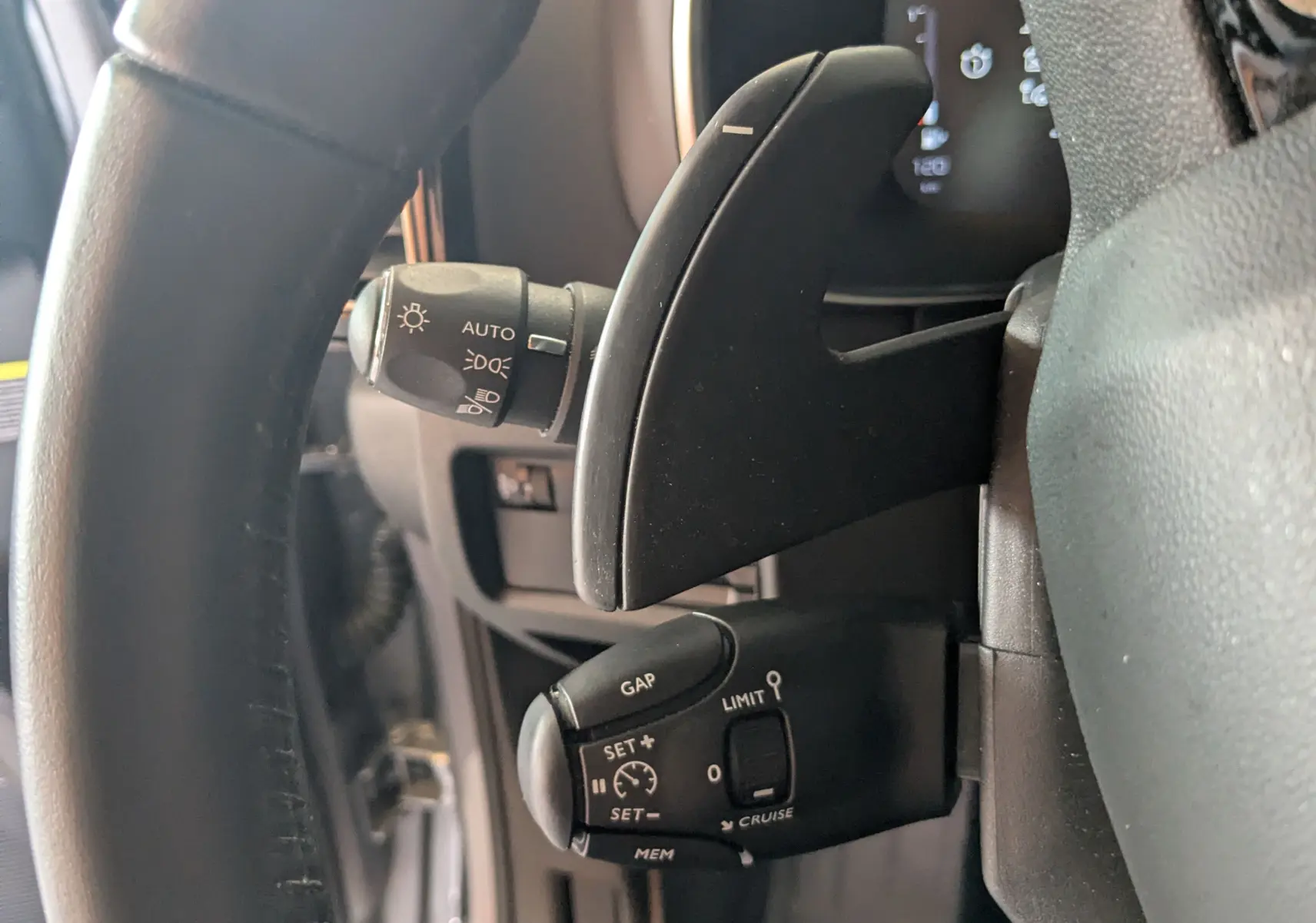 Gros plan sur la commande de régulateur de vitesse et palettes au volant du Citroën C5 Aircross gris Artens 2024.