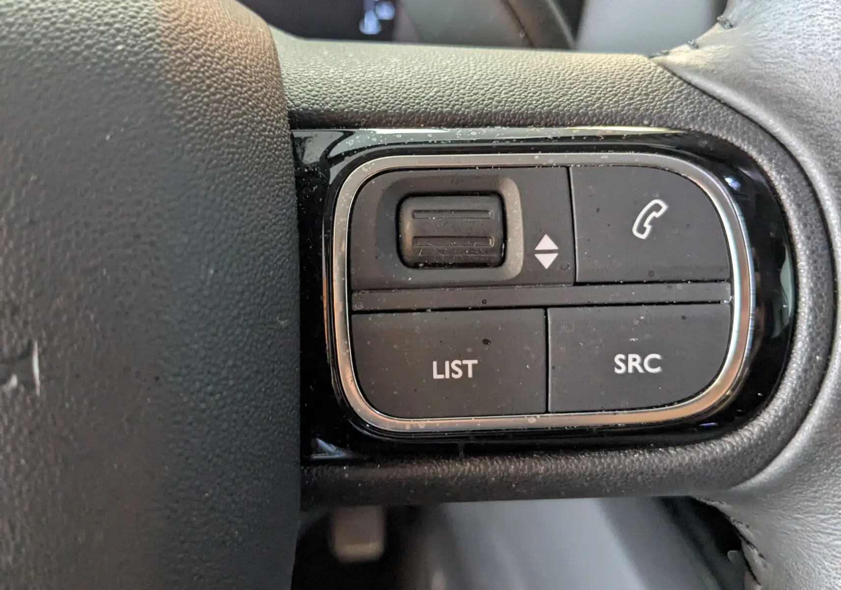 Gros plan sur les commandes au volant droit du Citroën C5 Aircross gris Artens 2024, boutons LIST, SRC et téléphone.