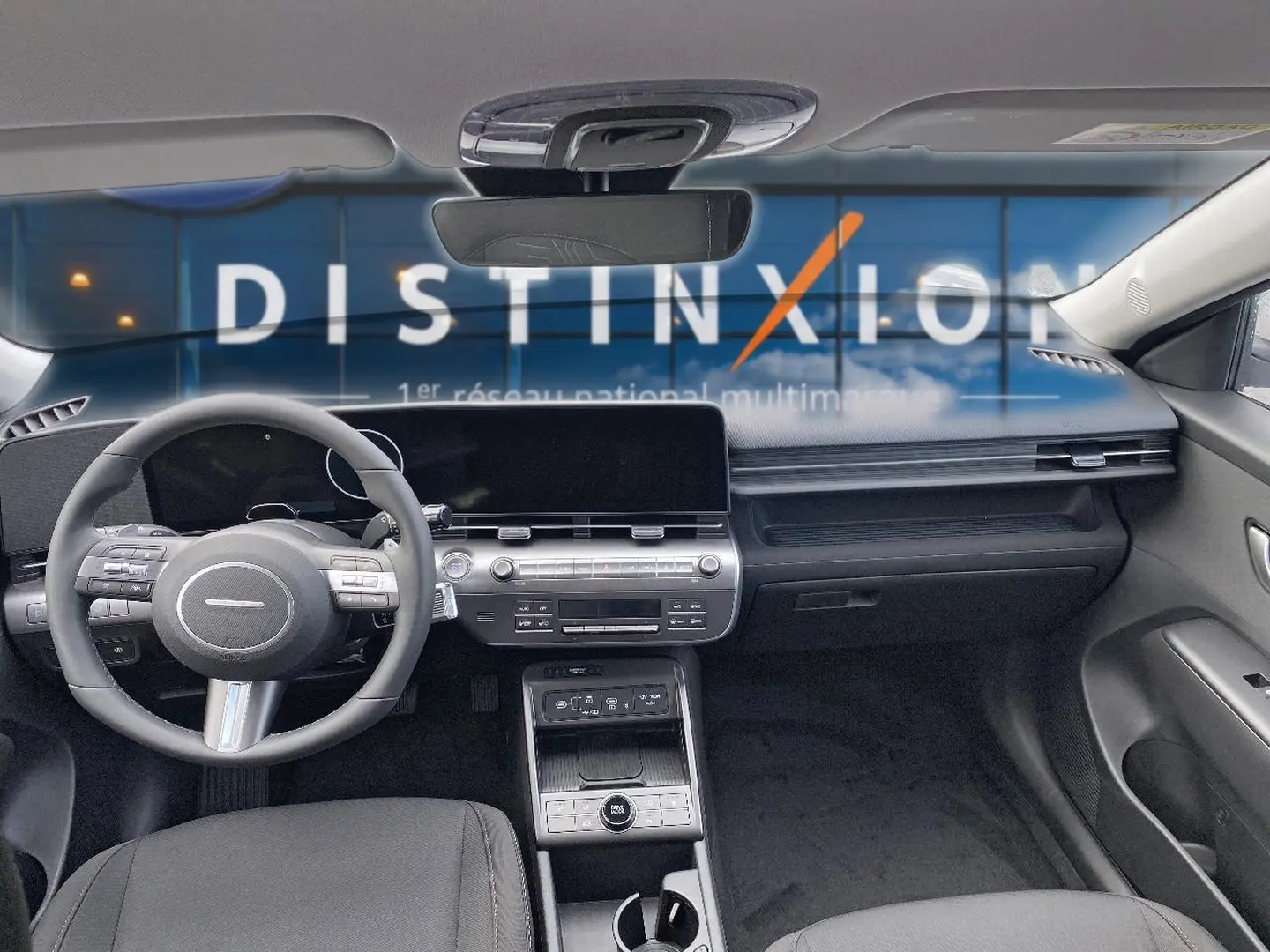 Vue intérieure avant du Hyundai Kona 2025 gris, montrant le volant cuir multifonction et l'écran tactile large.
