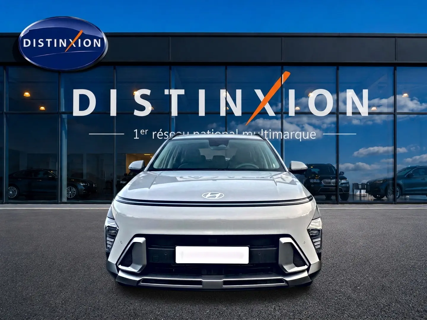 Vue de face du Hyundai Kona gris 2025 avec calandre minimaliste et feux LED fins, devant une vitrine Distinxion.