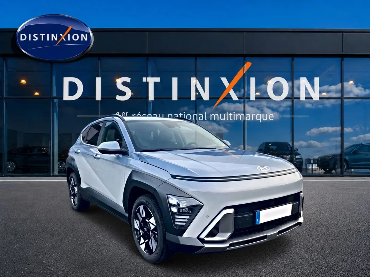 Hyundai Kona gris 2025 en 3/4 avant droit, avec jantes alliage et éclairage LED distinctif, devant vitrine Distinxion.