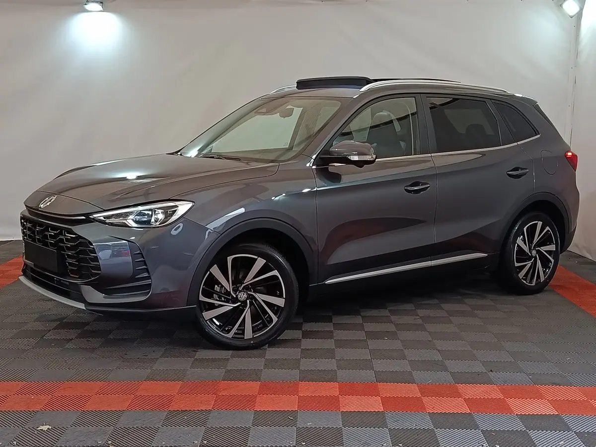 MG Motor ZS gris foncé en vue 3/4 avant droit, avec jantes alliage noires et toit ouvrant panoramique.