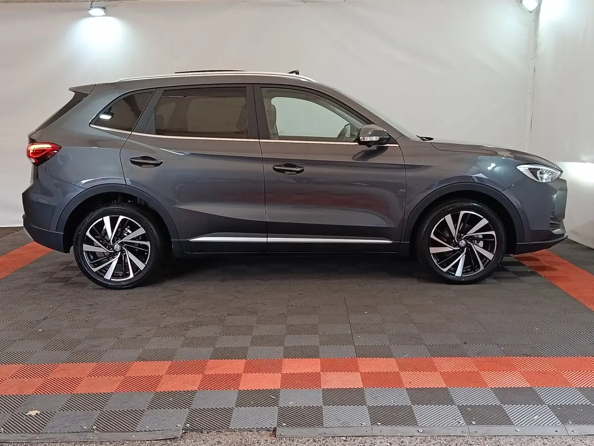 Vue de profil côté gauche du MG Motor ZS gris foncé 2026 avec jantes alliage et feux arrière allumés.