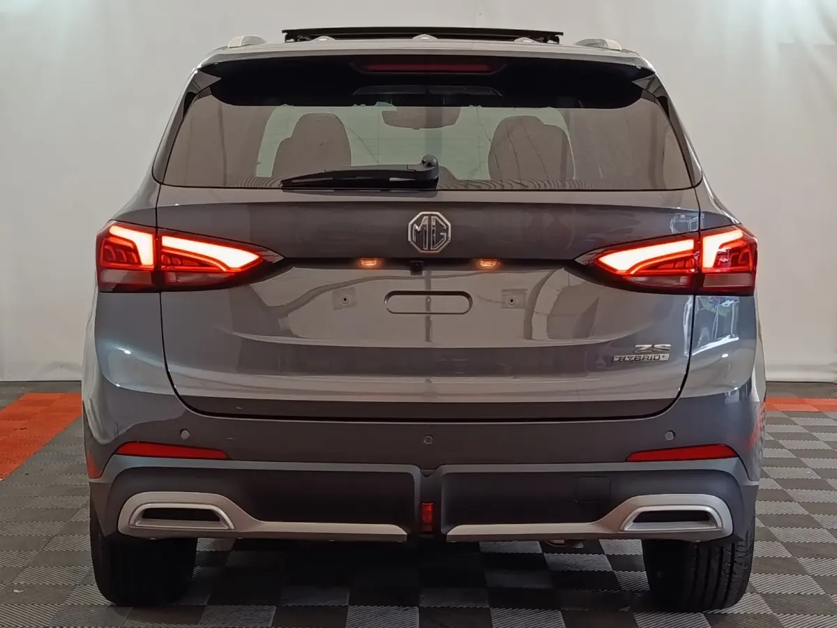 Vue arrière du SUV MG ZS gris foncé avec feux LED allumés et double sortie d’échappement intégrée au pare-chocs.