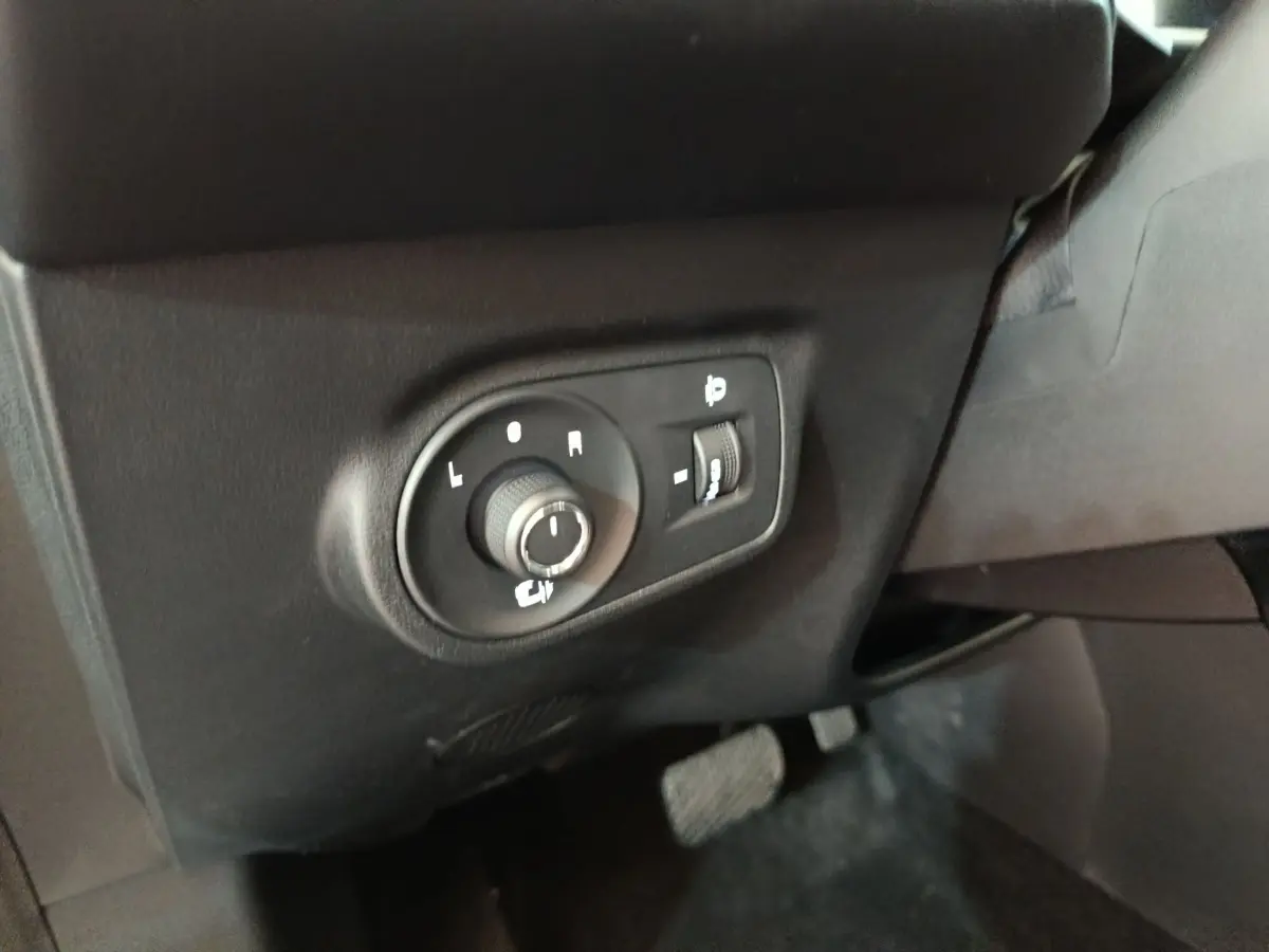 Gros plan sur les commandes de réglage des rétroviseurs intérieurs d’un MG Motor ZS gris foncé, côté conducteur.