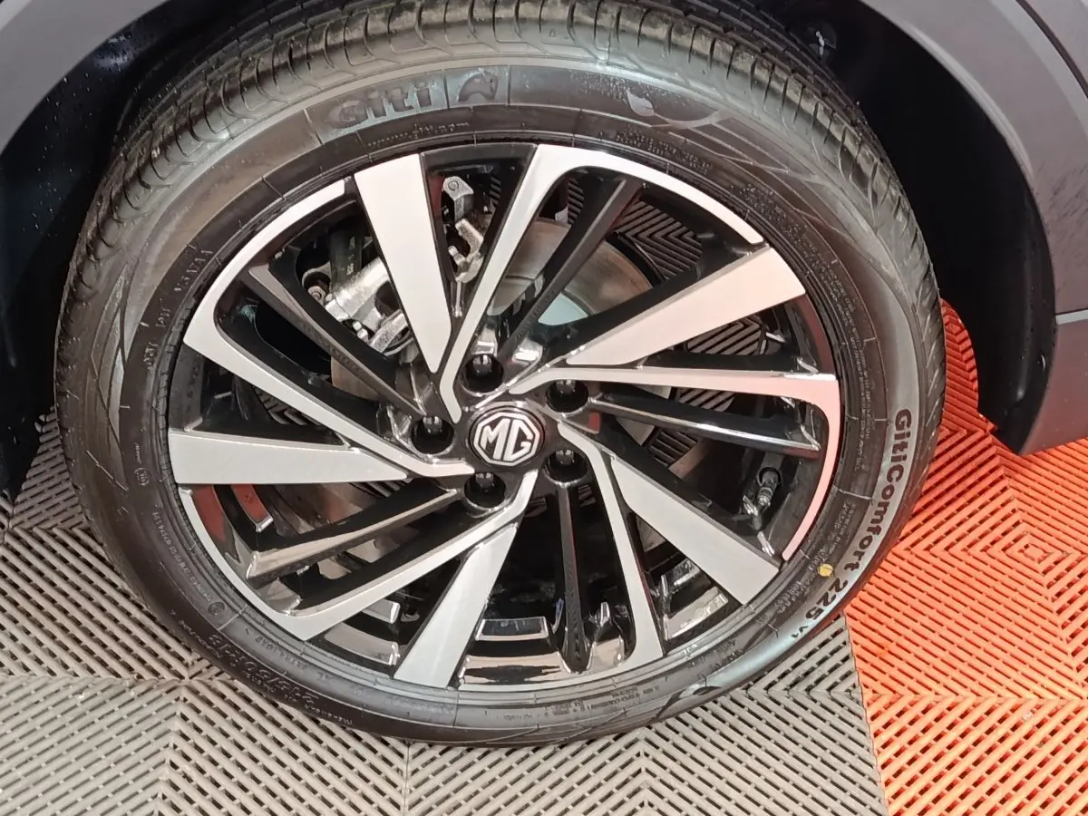 Gros plan sur la jante alliage bicolore noir et argent avec logo MG, entourée d’un pneu gris foncé du MG ZS Hybrid+ Luxury.