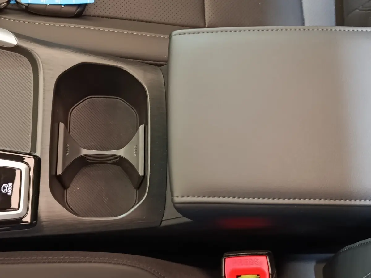 Gros plan sur l'accoudoir central gris et porte-gobelets noirs du MG Motor ZS hybride 2026, intérieur moderne.