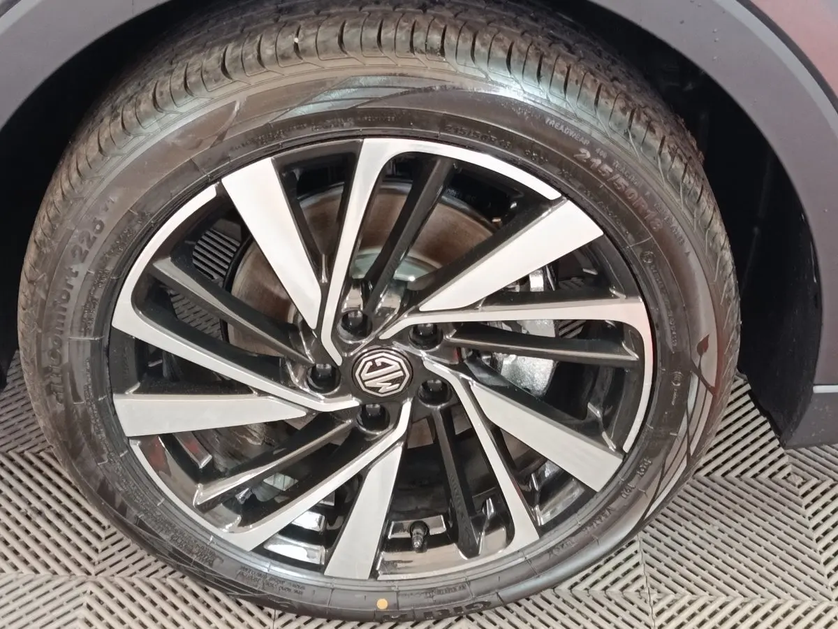 Gros plan sur la roue avant droite du MG ZS gris foncé, jante alliage bicolore avec logo MG au centre.