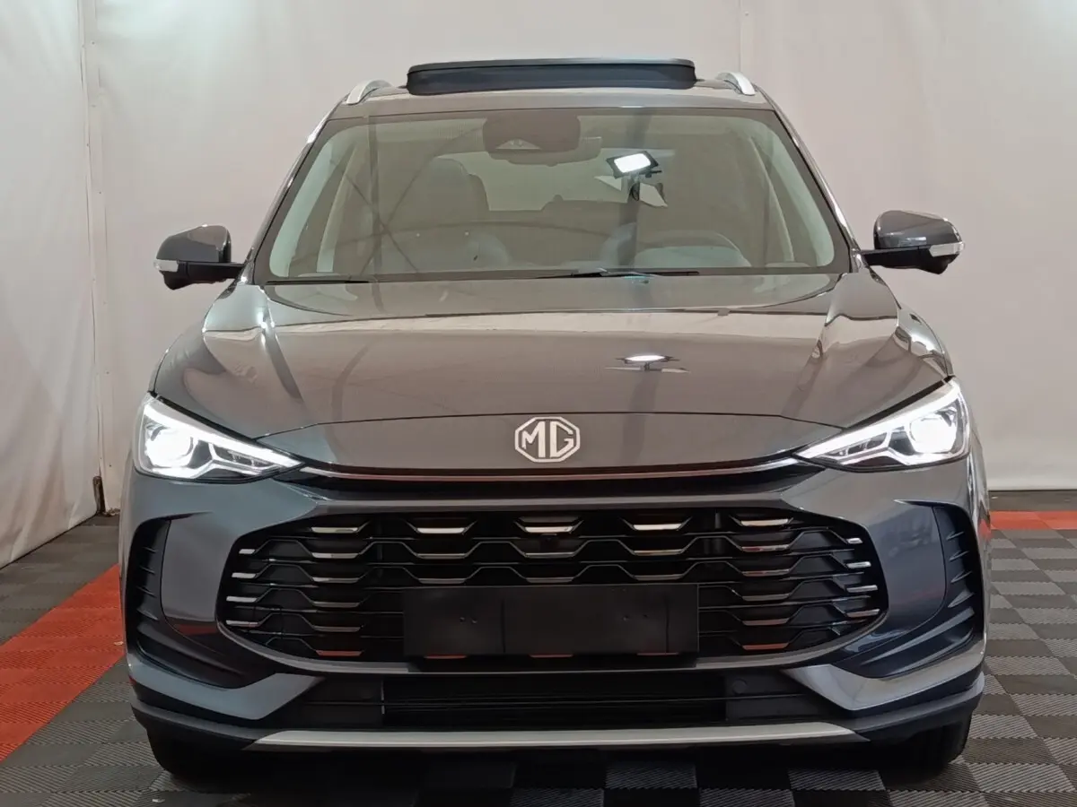 Vue frontale du MG ZS gris foncé 2026 avec phares LED allumés et calandre imposante noire.