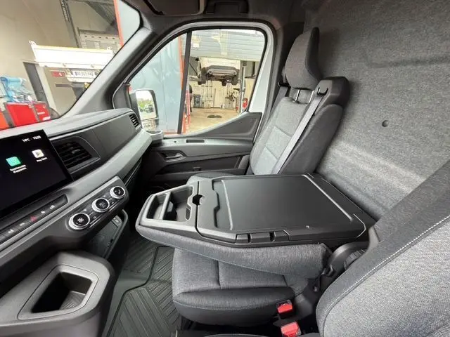 Intérieur du Renault Master blanc 2025, vue côté passager avec banquette et bureau mobile déployé en tissu gris.