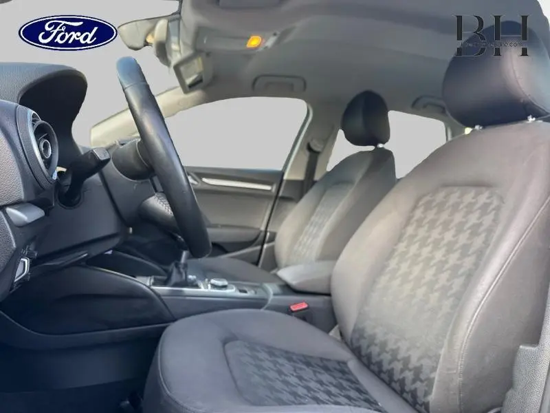 Intérieur avant de l'Audi A3 Sportback 2016 noir, vue côté conducteur montrant sièges et volant cuir multifonction.